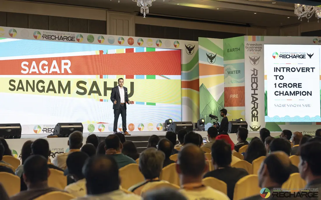 Sagar Sangam Sahu on stage at a live event for coaches, under a banner that reads Introvert to 1 Crore Champion